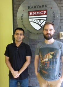 Two young men in front of HNMCP logo