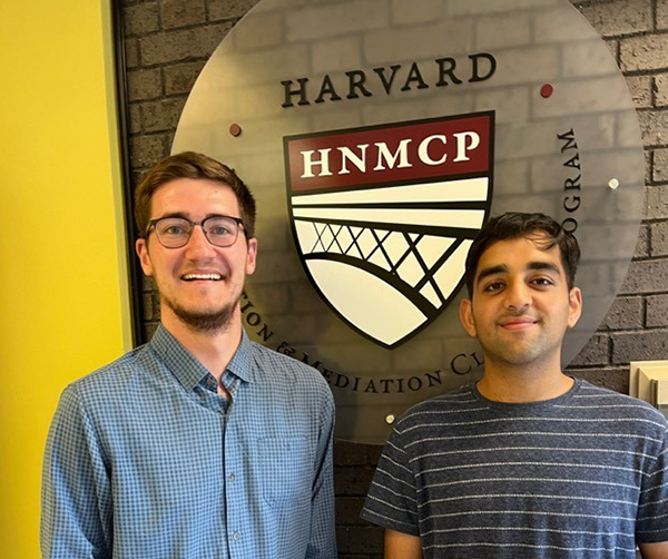 Two men standing in front of HNMCP logo