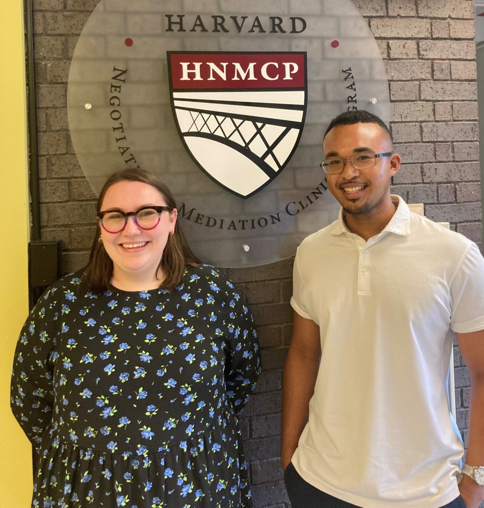 A woman and man standing in front of the HNMCP Logo