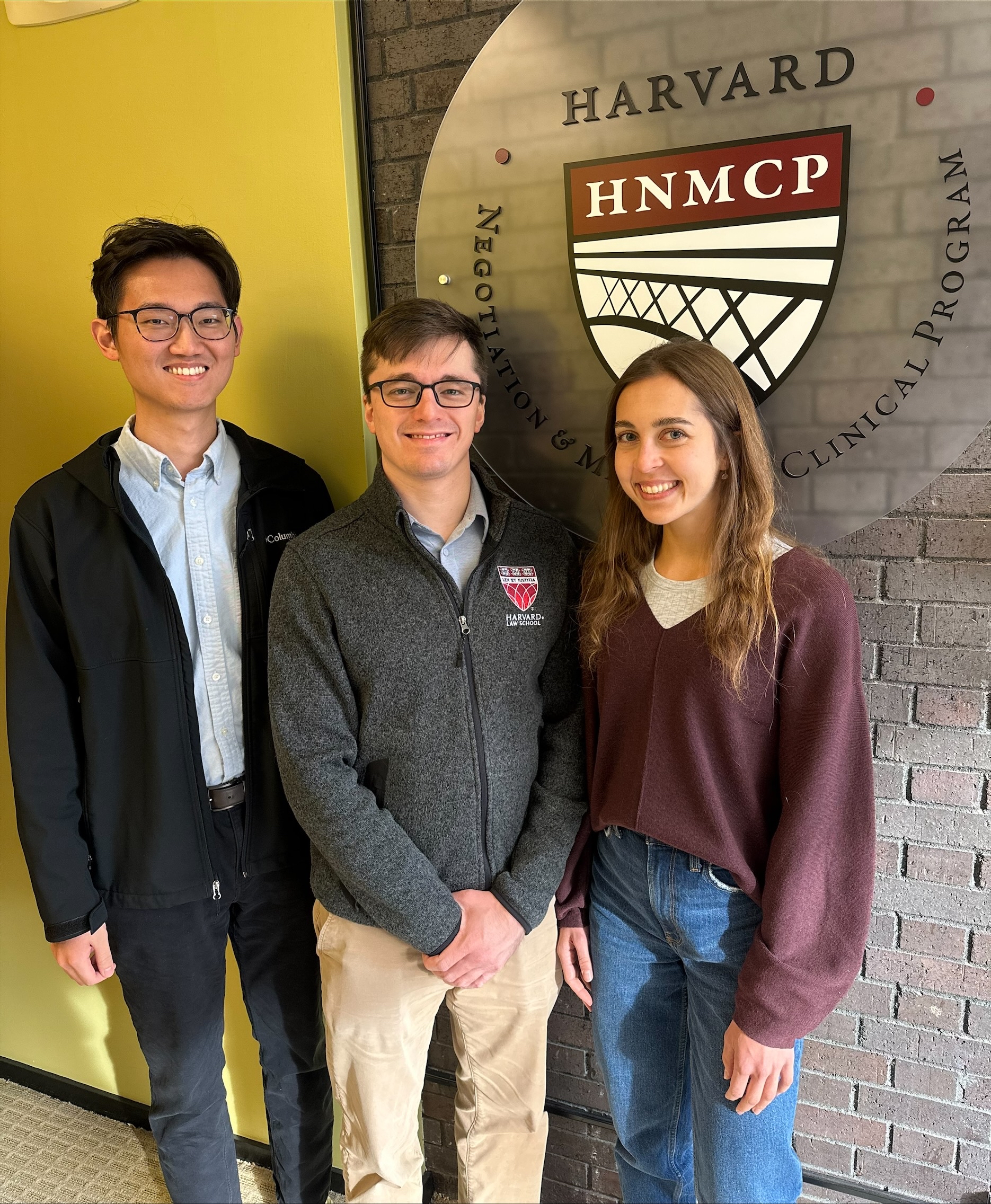 picture of two men and a woman standing in front of the HNMCP logo